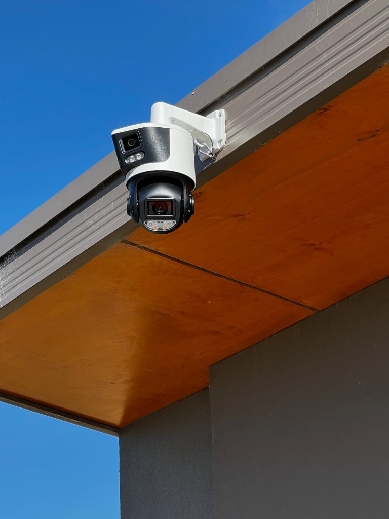 Dual-lens PTZ camera mounted under a timber-lined eave